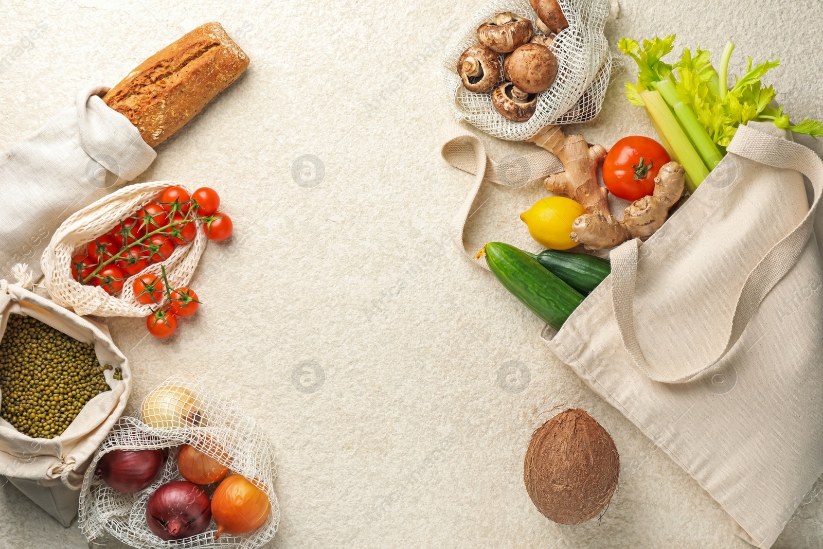 Photo of Eco bags with different food products on white textured table, flat lay. Space for text