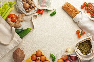 Photo of Eco bags with different food products on white textured table, flat lay. Space for text