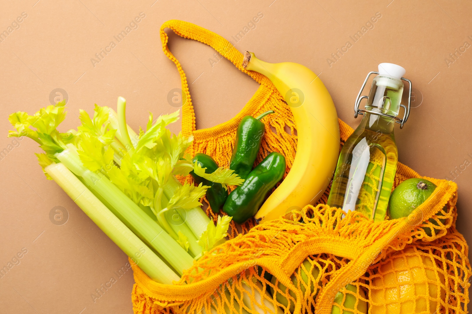 Photo of Eco bag with vegetables, fruits and bottle of drink on dark beige background, top view