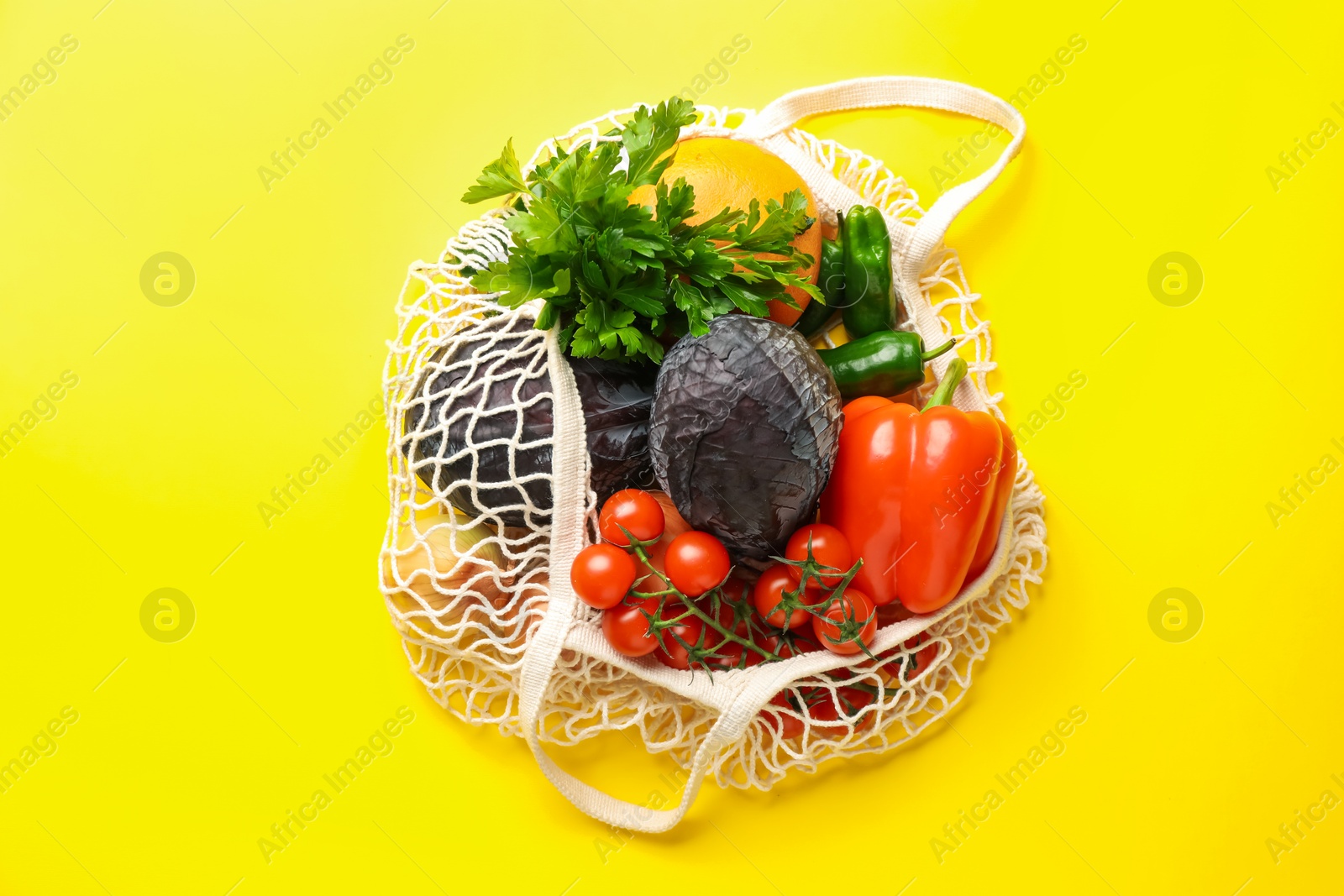 Photo of Eco bag with vegetables and grapefruit on yellow background, top view