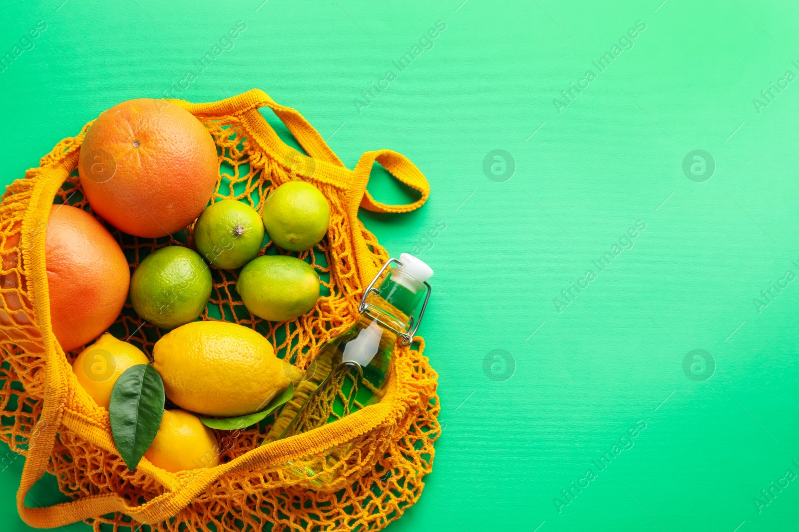 Photo of Eco bag with fruits and bottle of drink on green background, top view. Space for text