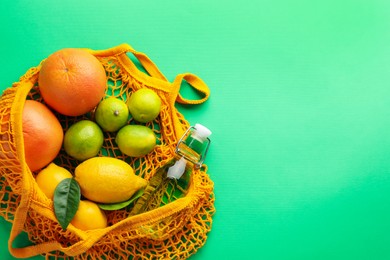 Photo of Eco bag with fruits and bottle of drink on green background, top view. Space for text