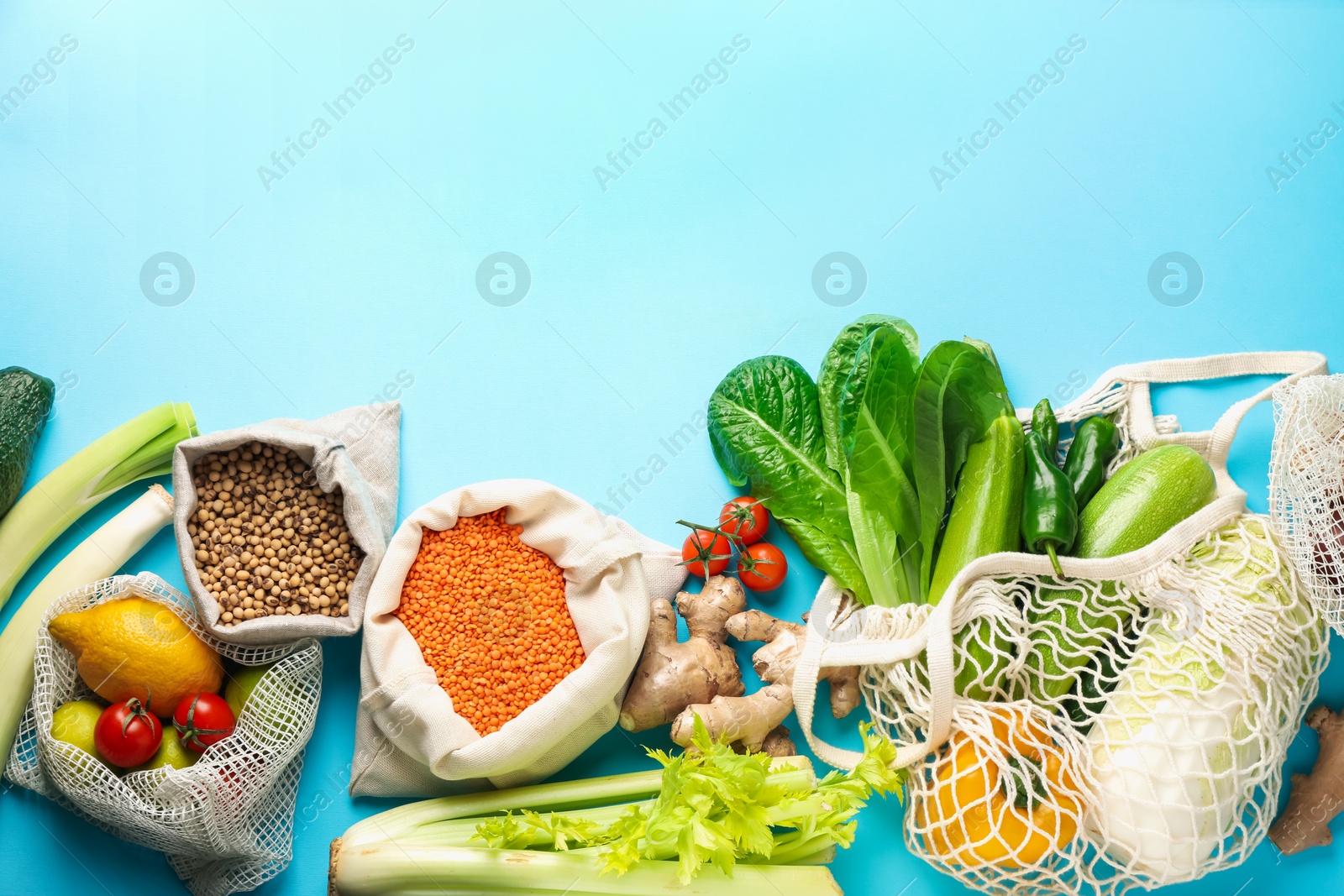 Photo of Shopper bags with products on light blue background, flat lay and space for text. Eco friendly lifestyle