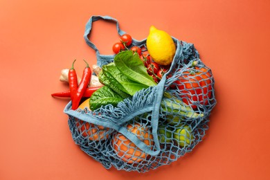 Photo of Net bag with products on orange background, top view. Eco friendly lifestyle