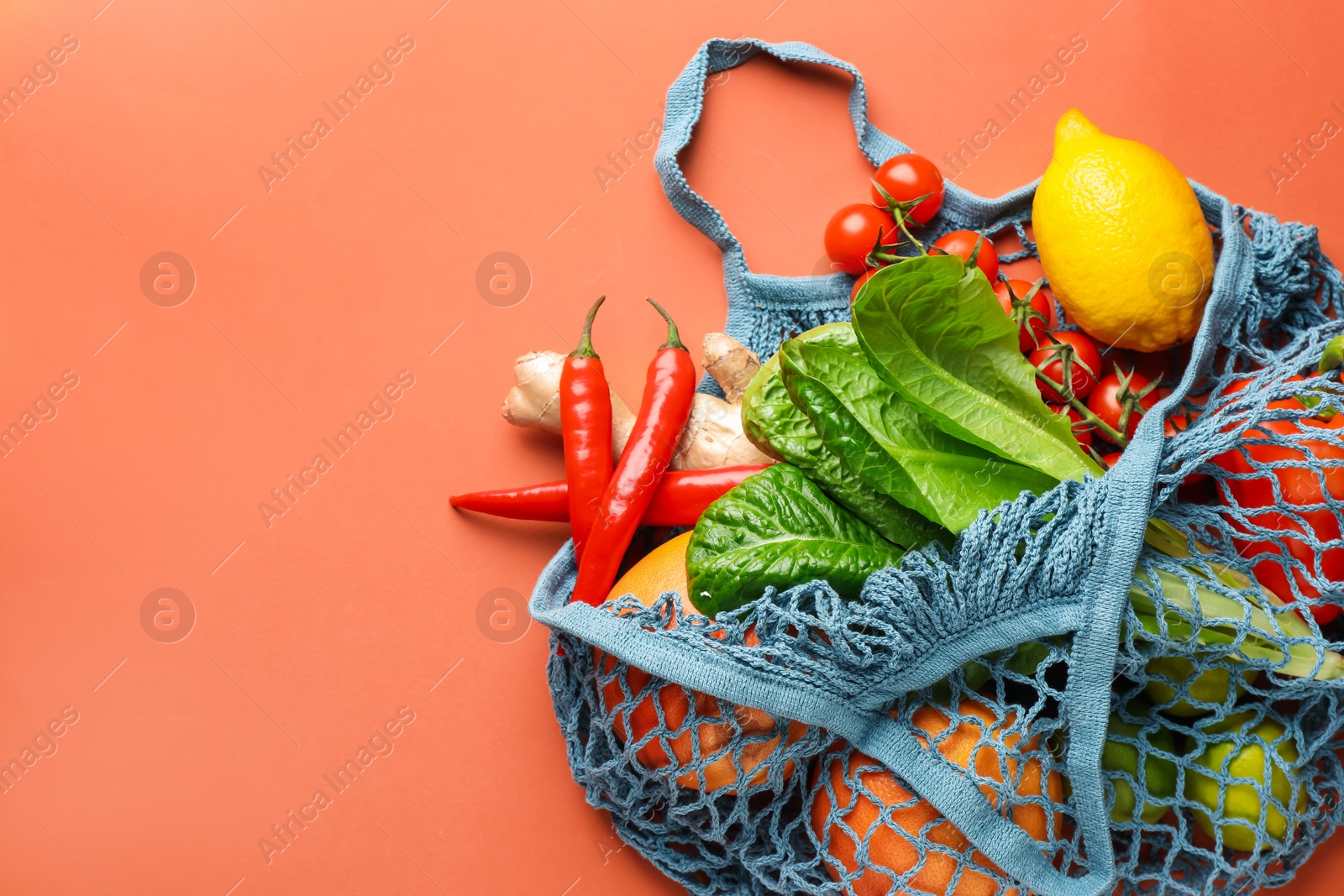 Photo of Net bag with products on orange background, top view and space for text. Eco friendly lifestyle