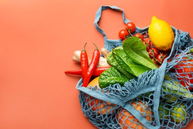 Photo of Net bag with products on orange background, top view and space for text. Eco friendly lifestyle