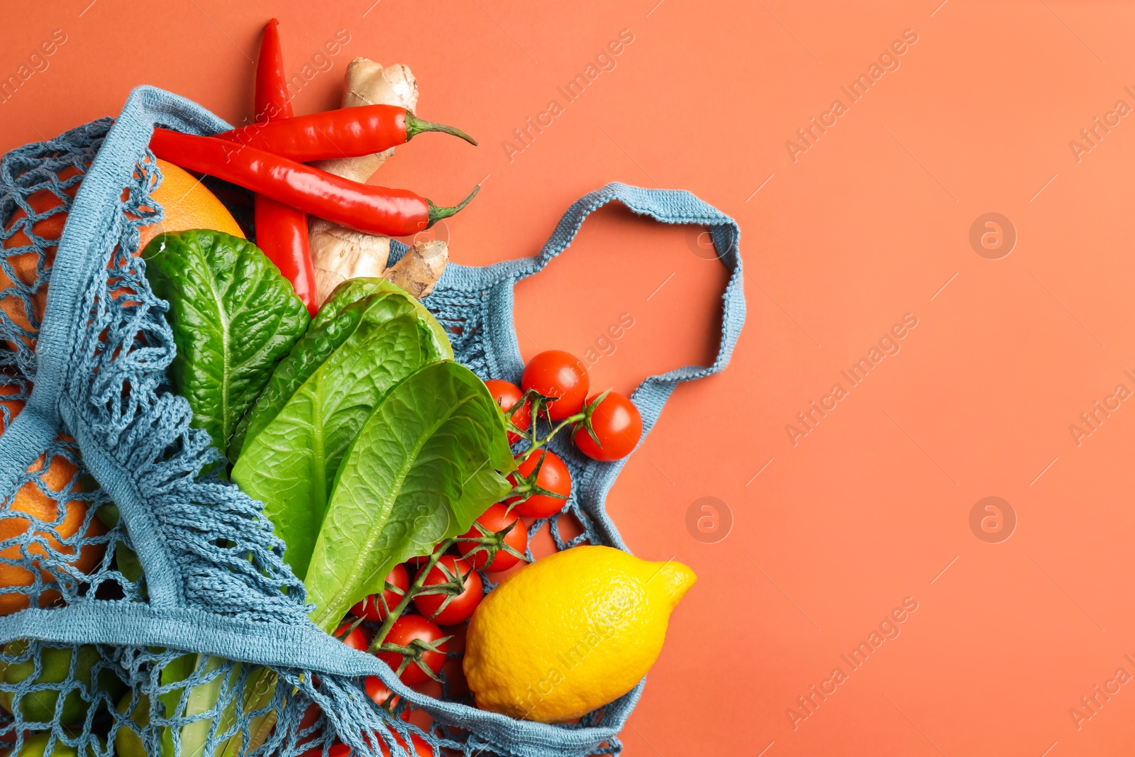 Photo of Net bag with products on orange background, top view and space for text. Eco friendly lifestyle