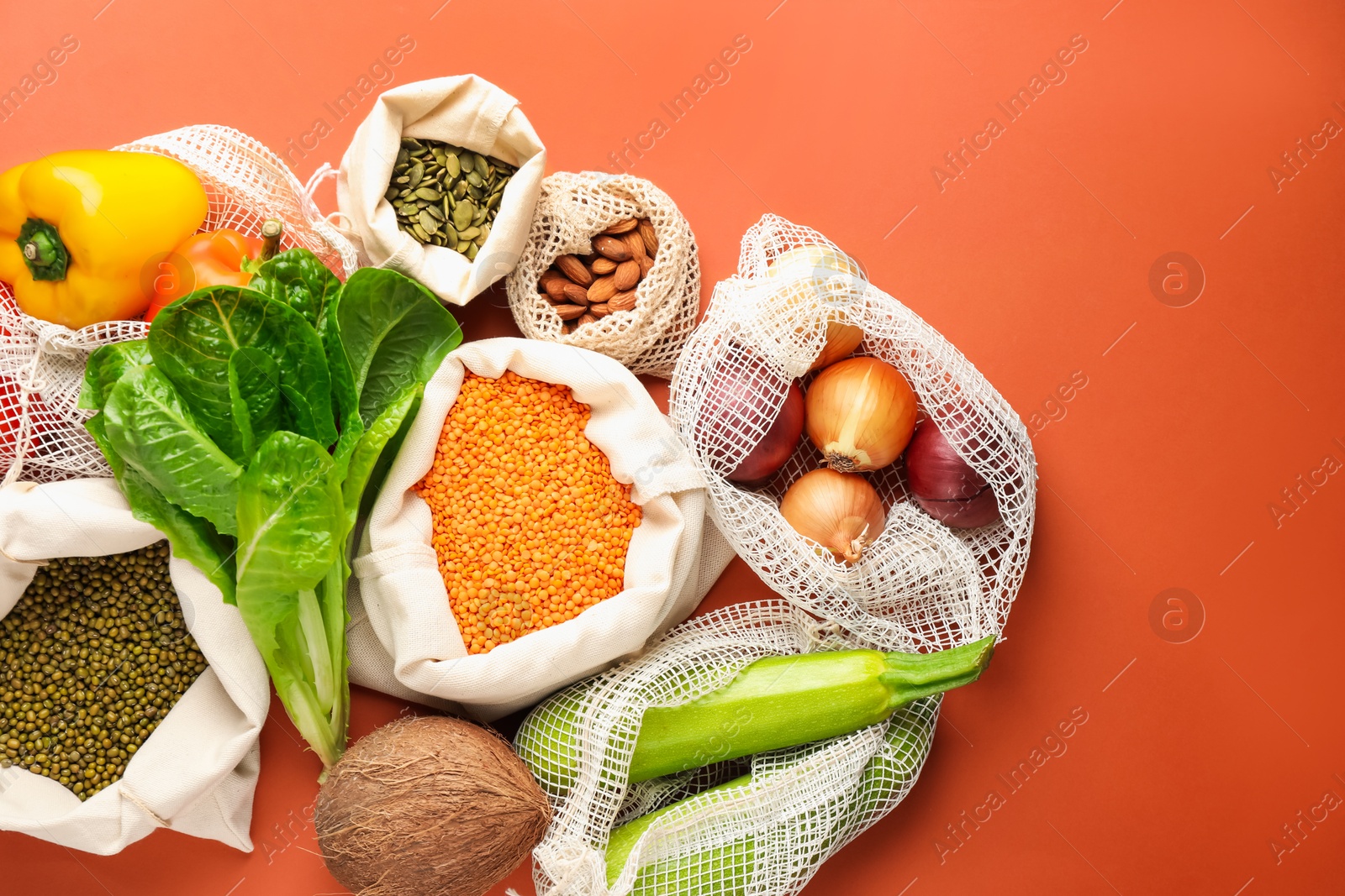 Photo of Shopper bags with products on orange background, flat lay. Eco friendly lifestyle