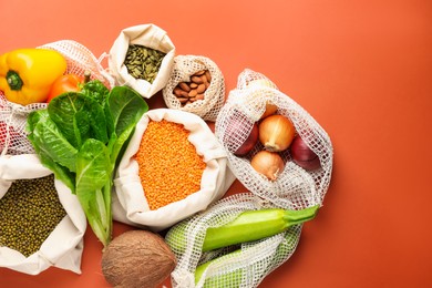 Photo of Shopper bags with products on orange background, flat lay. Eco friendly lifestyle