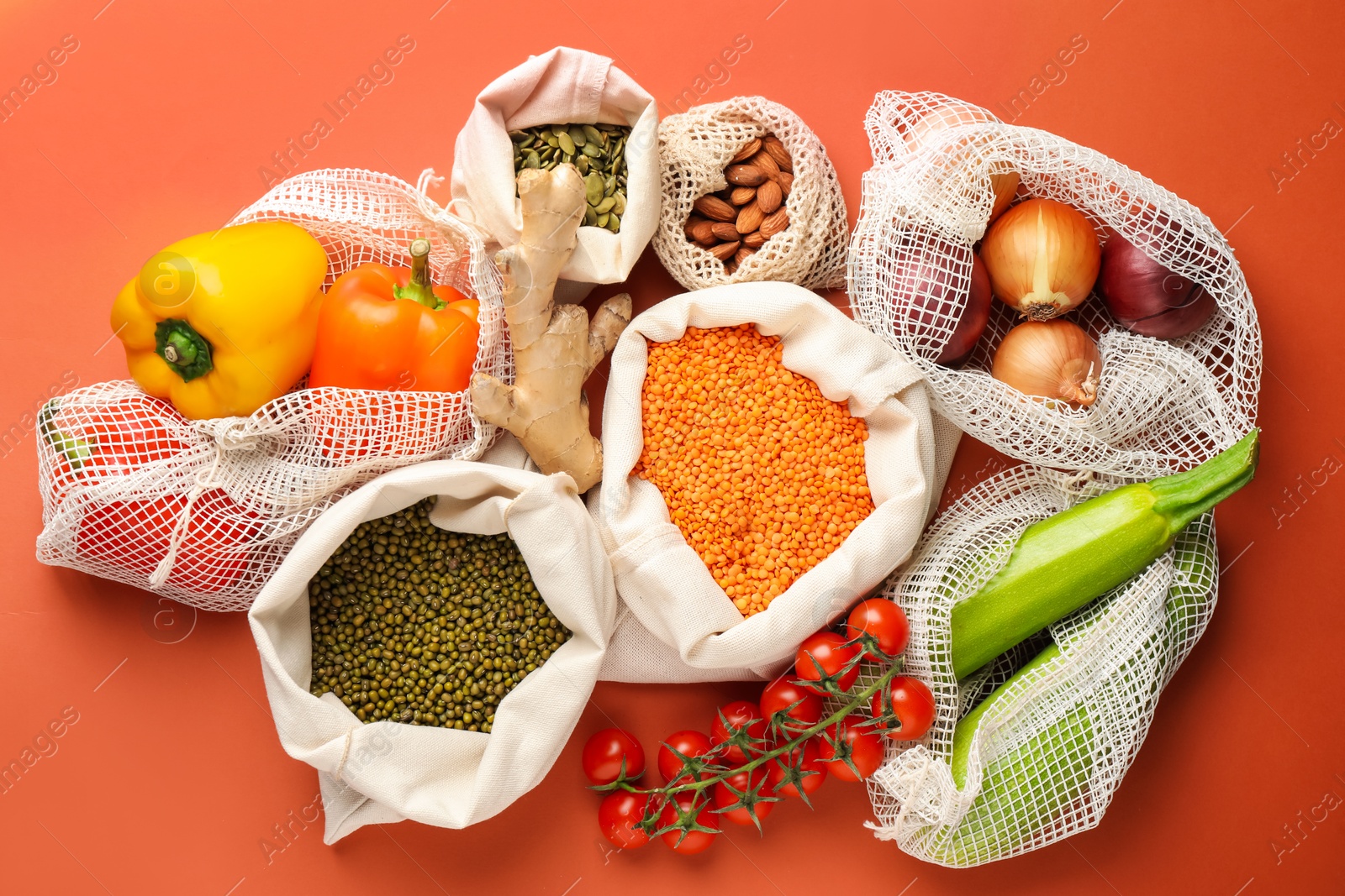 Photo of Shopper bags with products on orange background, flat lay. Eco friendly lifestyle