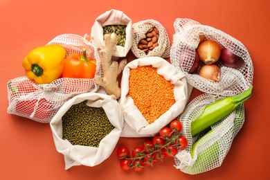 Photo of Shopper bags with products on orange background, flat lay. Eco friendly lifestyle