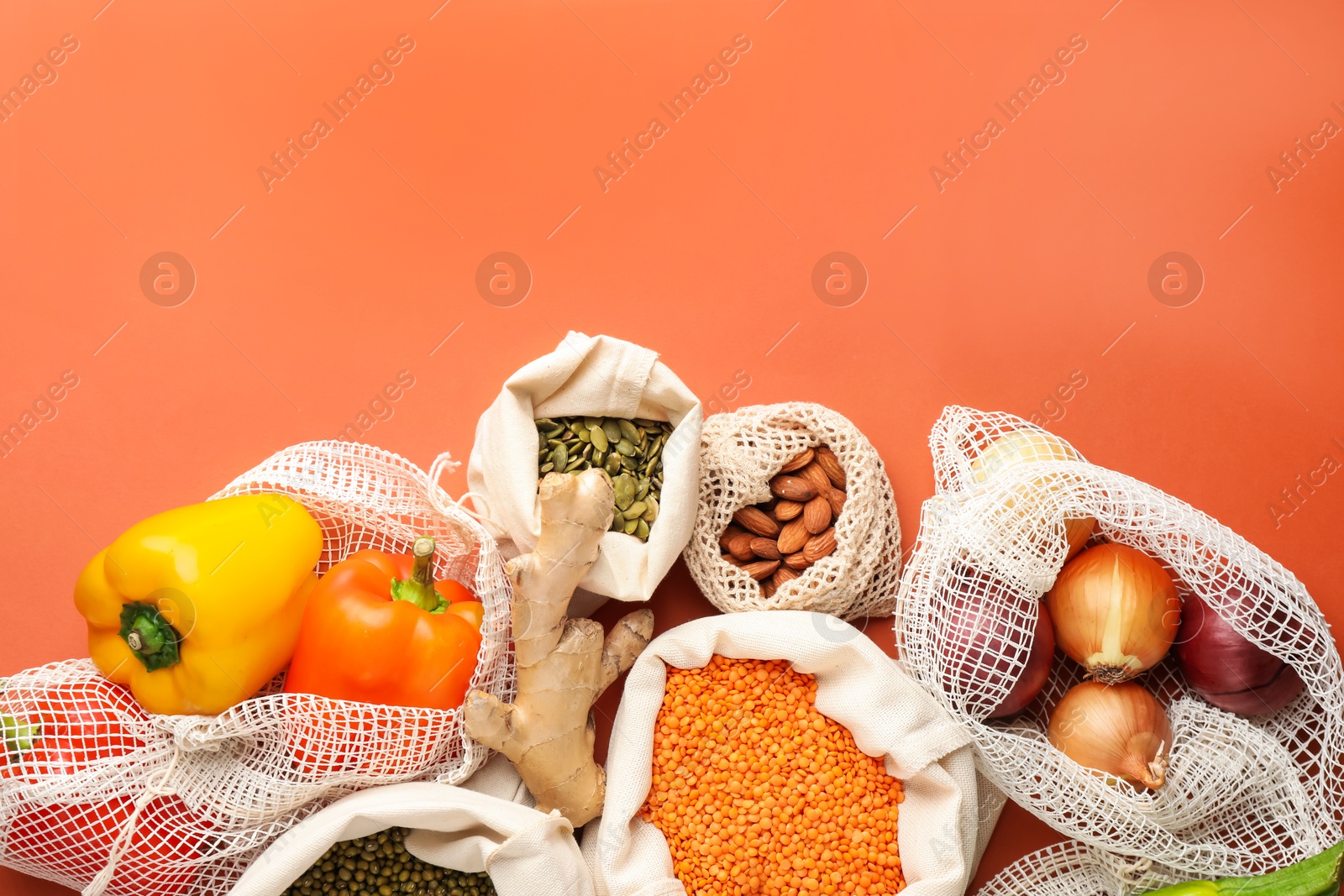 Photo of Shopper bags with products on orange background, flat lay and space for text. Eco friendly lifestyle