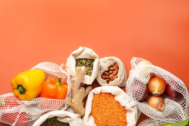 Photo of Shopper bags with products on orange background, flat lay and space for text. Eco friendly lifestyle