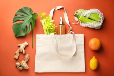 Photo of Shopper bag with products on orange background, flat lay. Eco friendly lifestyle