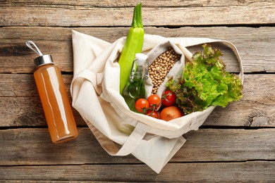 Photo of Shopper bag with products on wooden background, top view. Eco friendly lifestyle