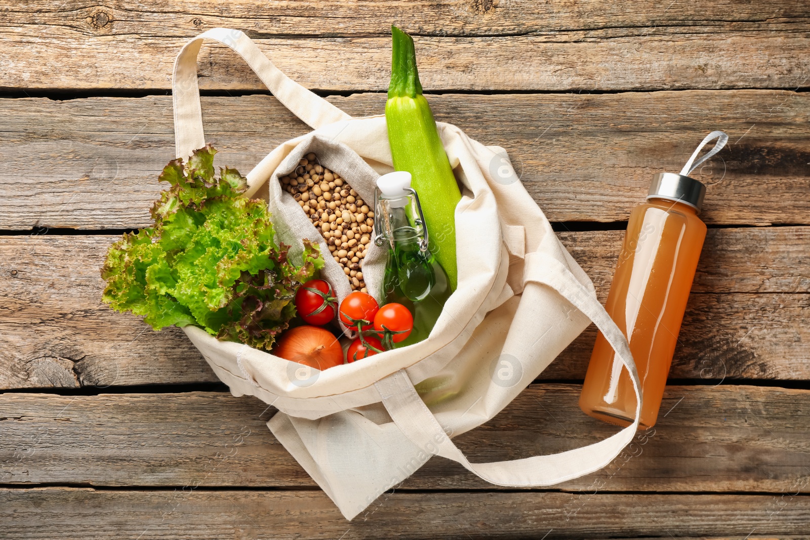 Photo of Shopper bag with products on wooden background, top view. Eco friendly lifestyle