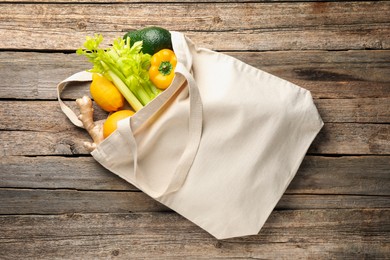 Photo of Shopper bag with products on wooden background, top view. Eco friendly lifestyle