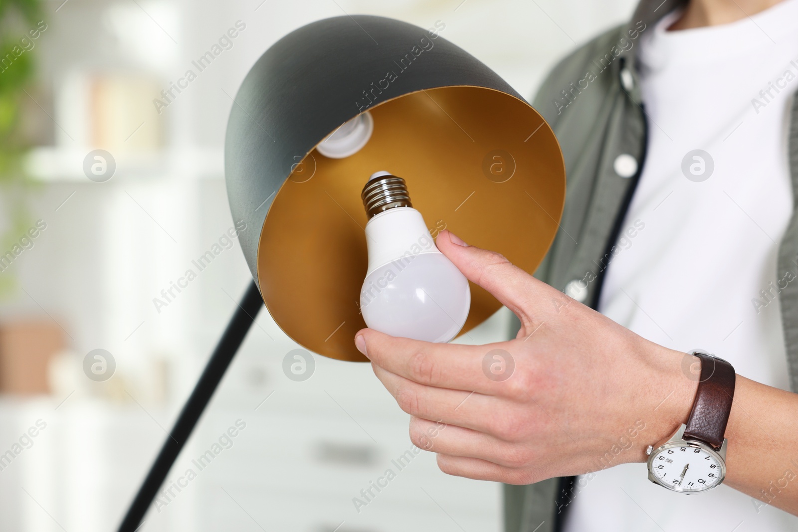 Photo of Man changing light bulb in lamp at home, closeup