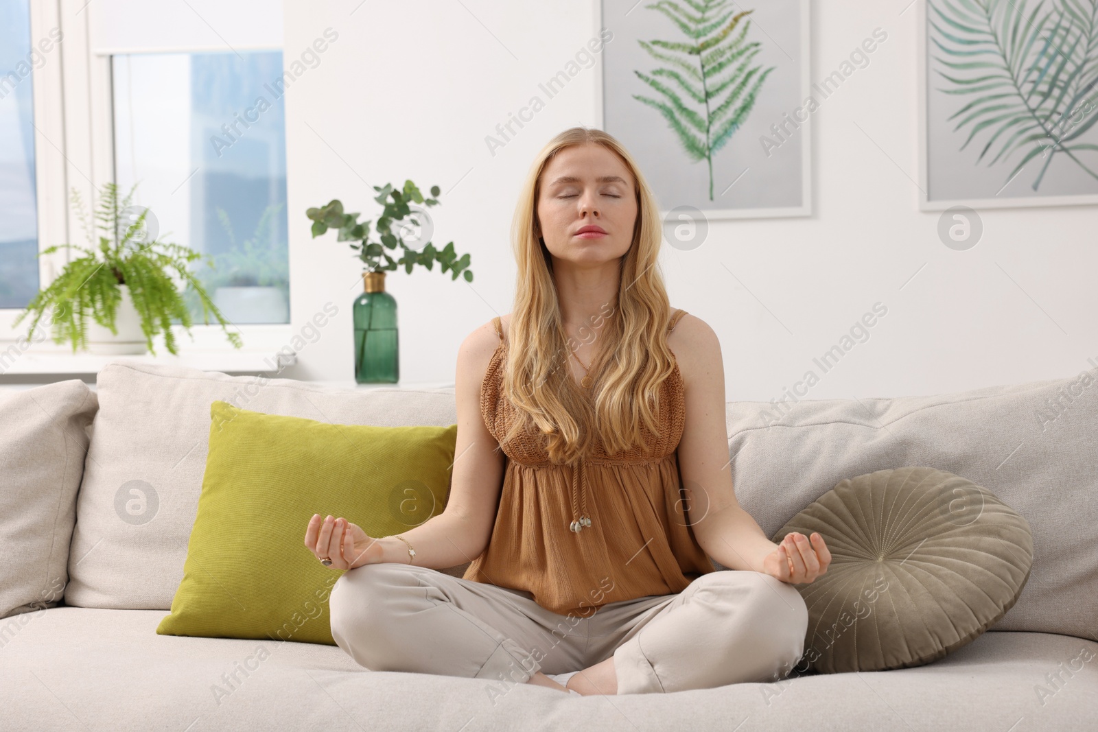 Photo of Feng shui. Young woman meditating on couch at home