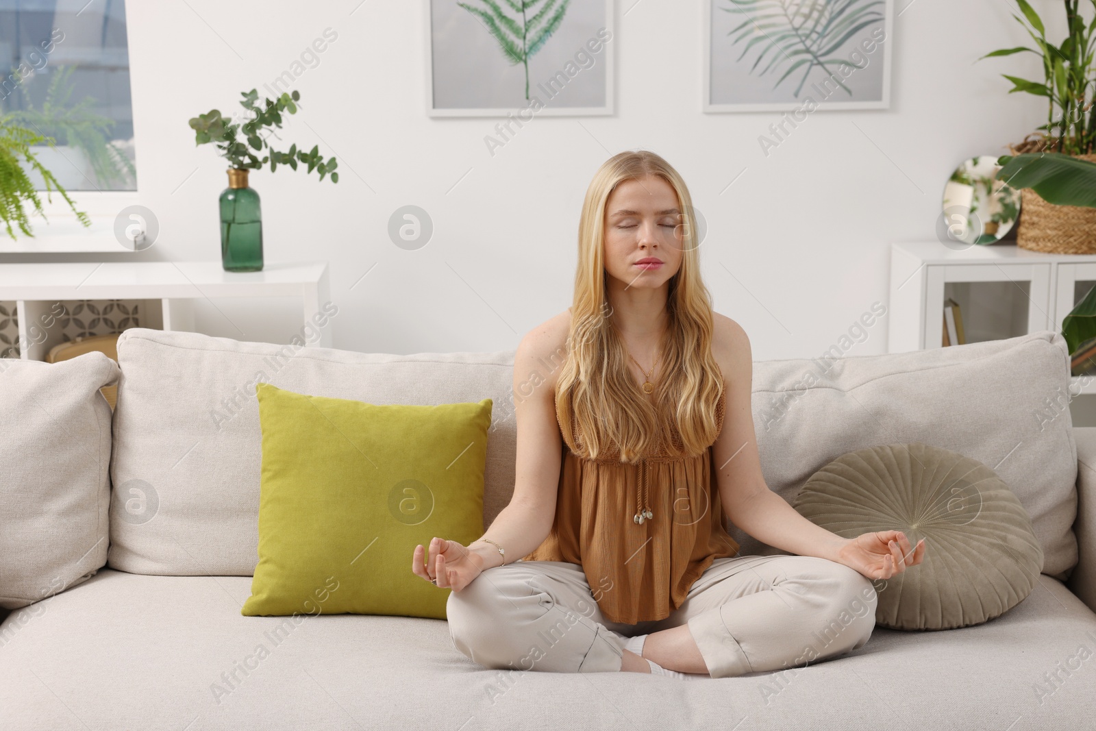 Photo of Feng shui. Young woman meditating on couch at home