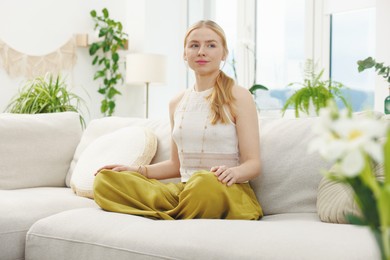 Photo of Feng shui. Young woman meditating on couch at home