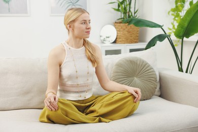 Feng shui. Young woman meditating on couch at home