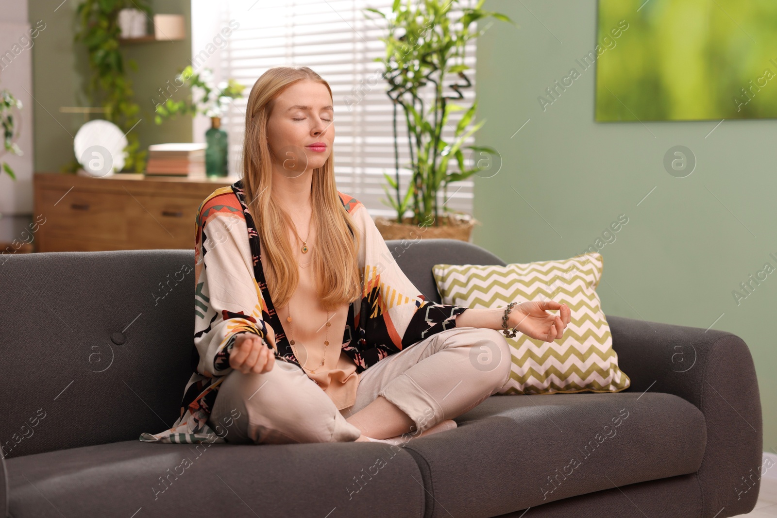 Photo of Feng shui. Young woman meditating on couch at home''