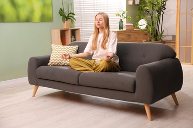 Feng shui. Young woman meditating on couch at home''