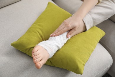 Photo of Woman with medical bandage on her foot at home, closeup