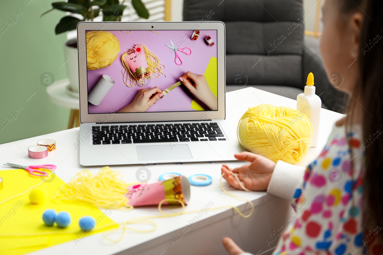 Photo of Little girl making handmade toy by following craft tutorial video at home. Child creativity