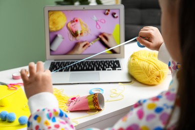 Photo of Little girl making handmade toy by following craft tutorial video at home. Child creativity