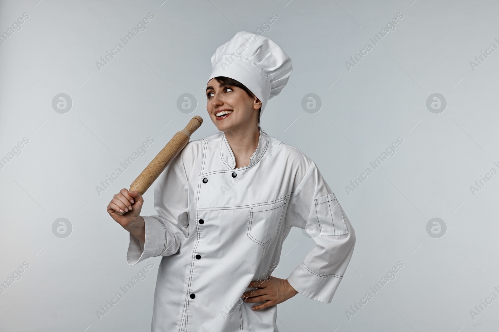 Photo of Professional chef with rolling pin on light grey background