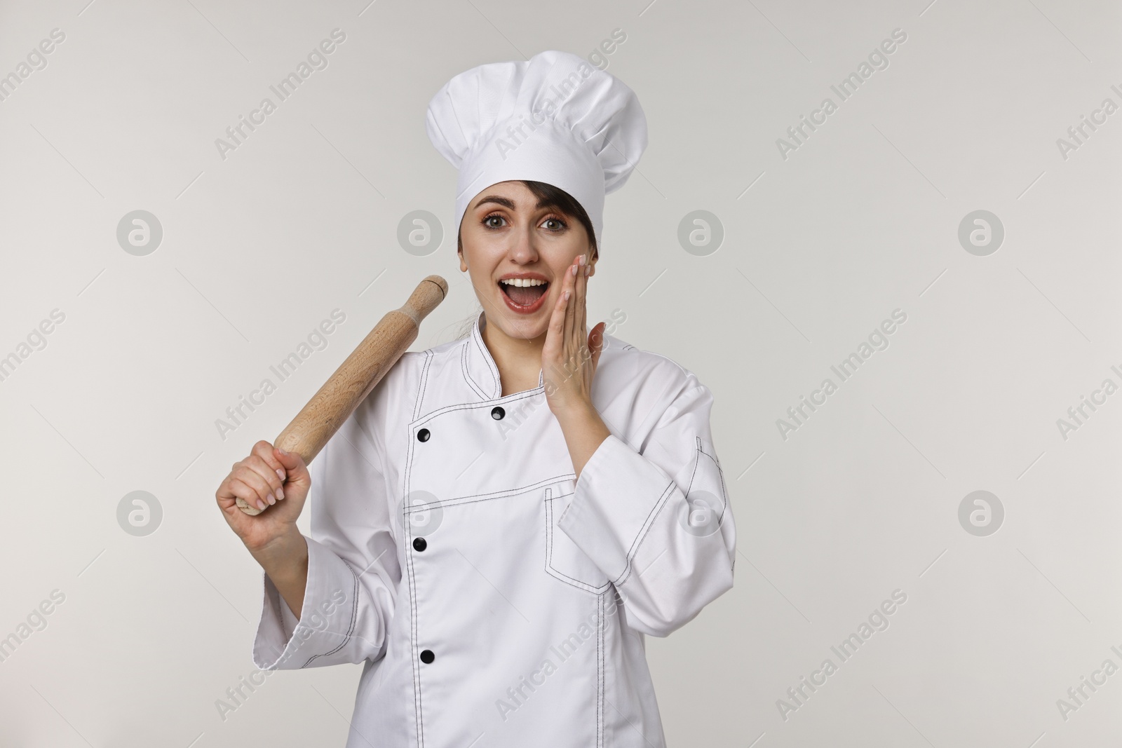 Photo of Emotional chef with rolling pin on light grey background