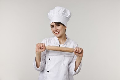 Photo of Professional chef with rolling pin on light grey background