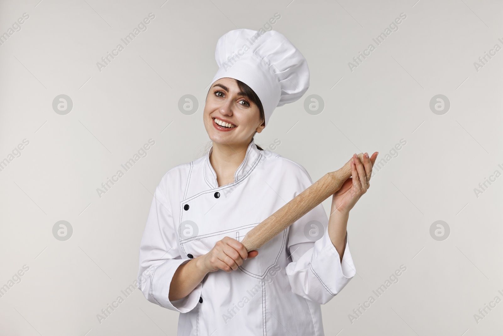 Photo of Professional chef with rolling pin on light grey background