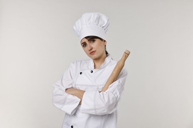 Photo of Professional chef with rolling pin on light grey background