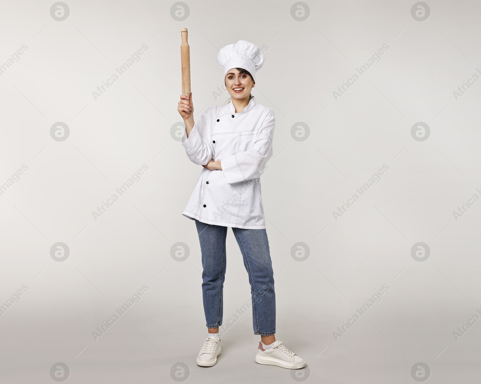 Photo of Professional chef with rolling pin on light grey background