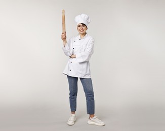 Professional chef with rolling pin on light grey background