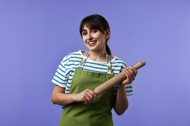 Photo of Happy woman with rolling pin on violet background