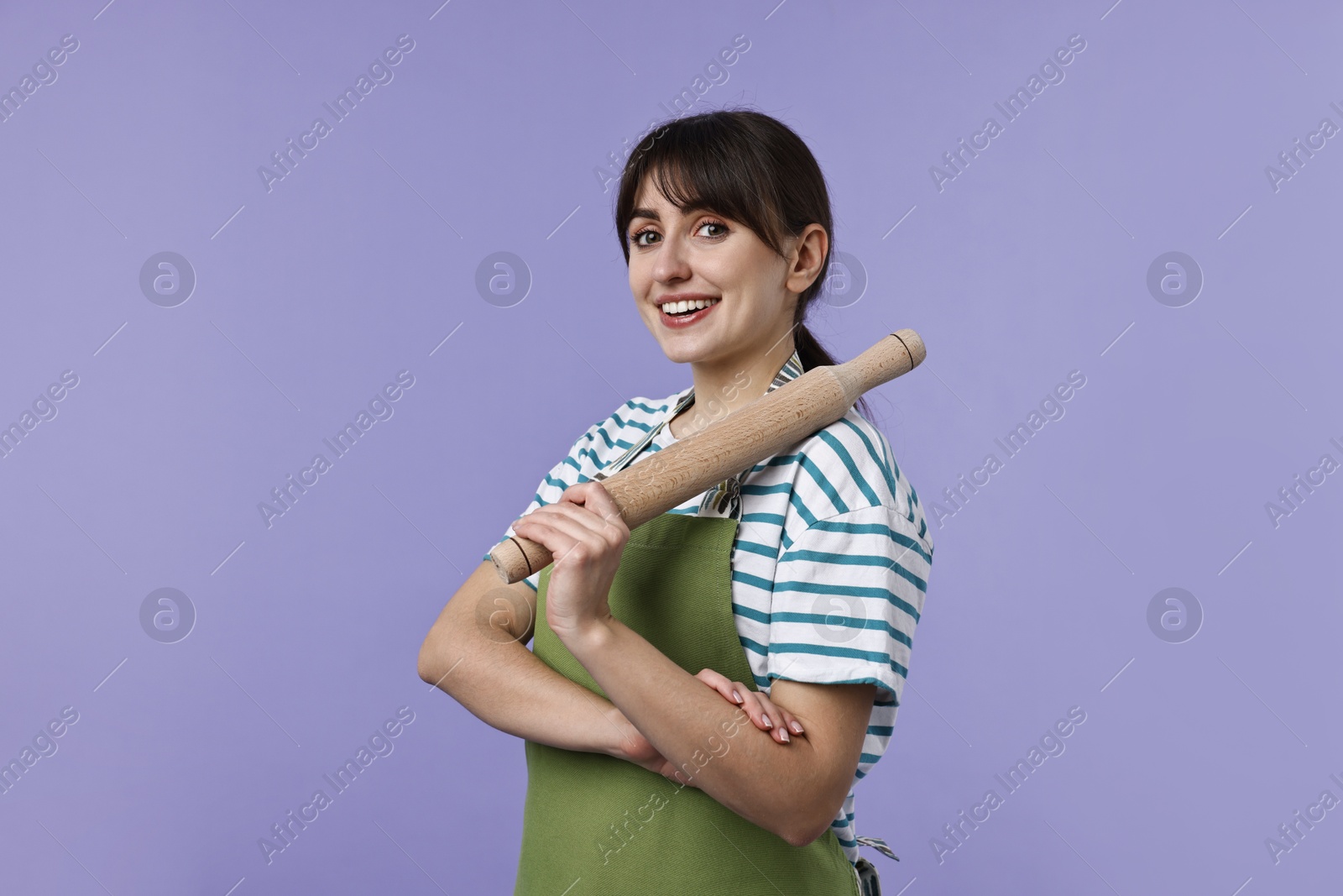 Photo of Happy woman with rolling pin on violet background