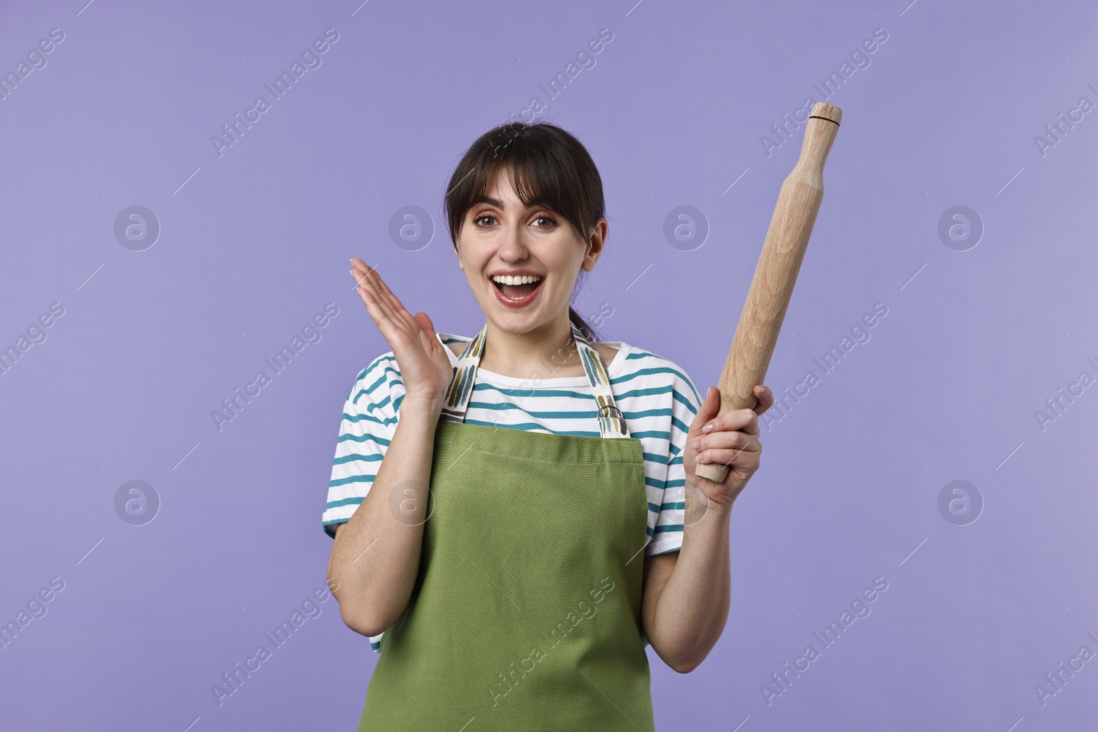 Photo of Excited woman with rolling pin on violet background