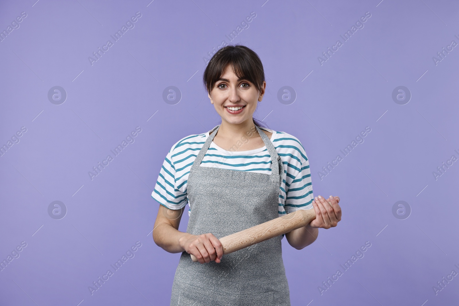 Photo of Happy woman with rolling pin on violet background