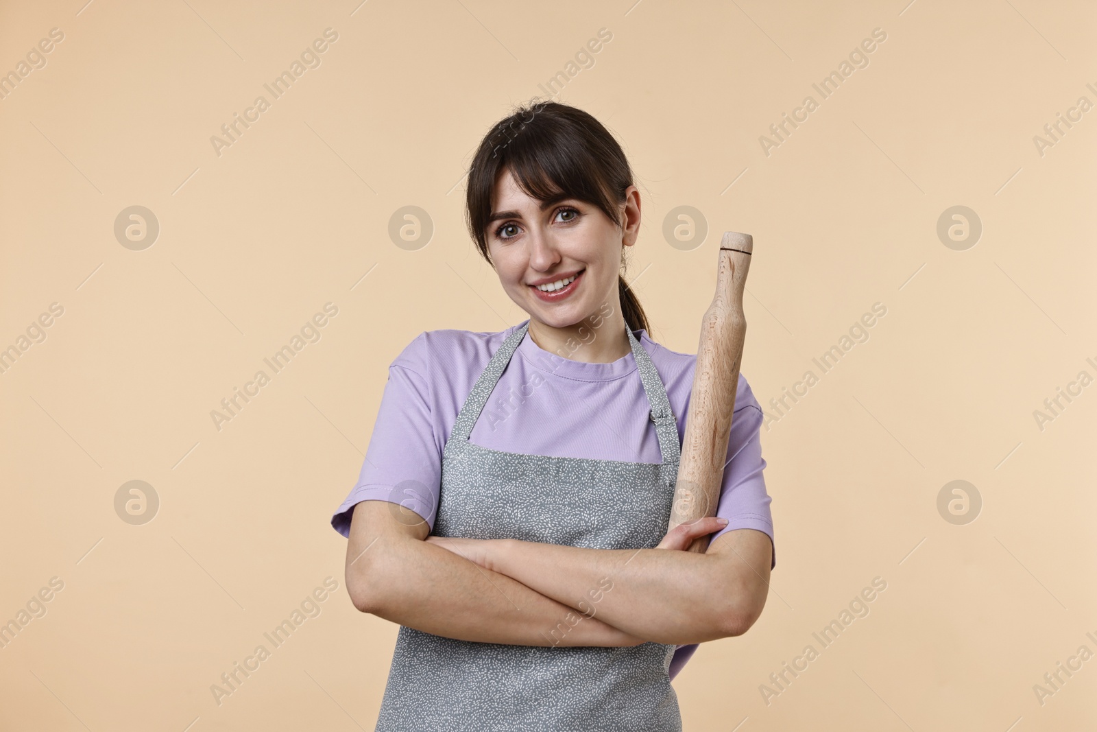 Photo of Happy woman with rolling pin on beige background