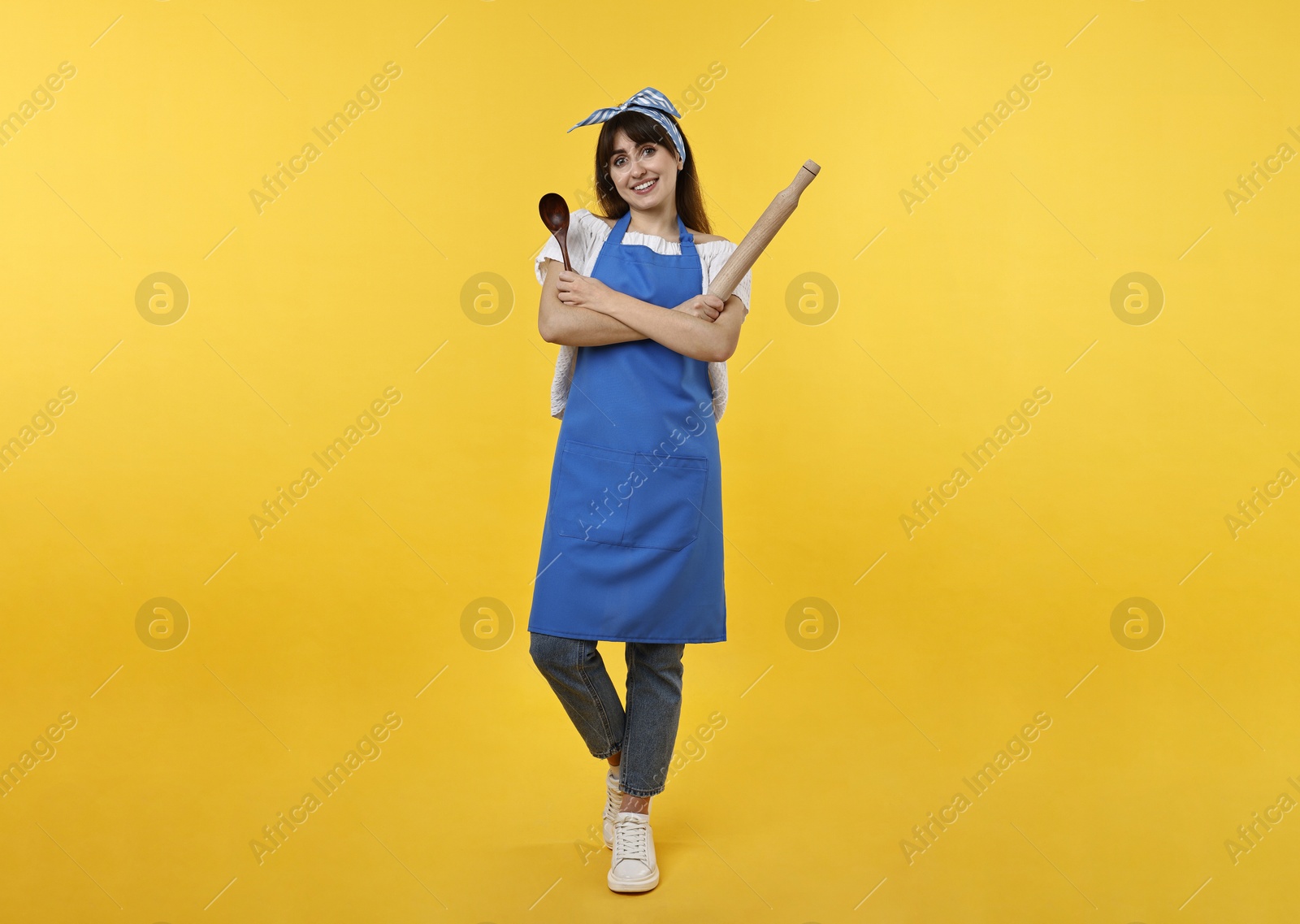 Photo of Woman with rolling pin and spoon on yellow background