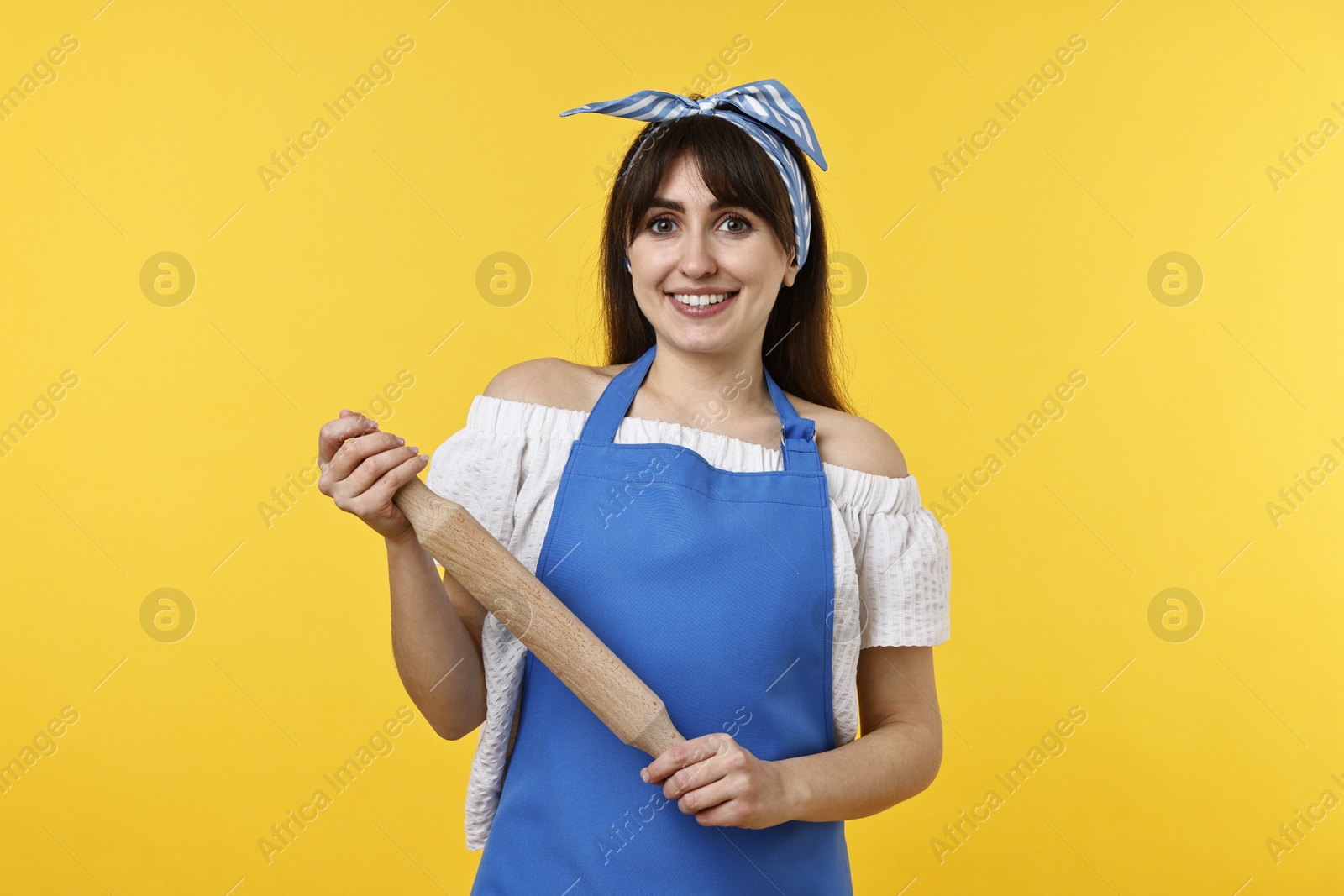 Photo of Happy woman with rolling pin on yellow background