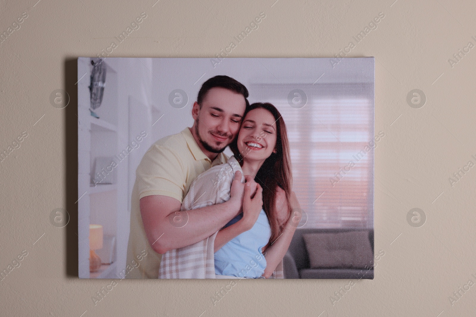 Photo of Canvas with printed photo of happy couple on beige wall indoors