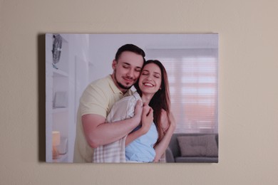 Canvas with printed photo of happy couple on beige wall indoors