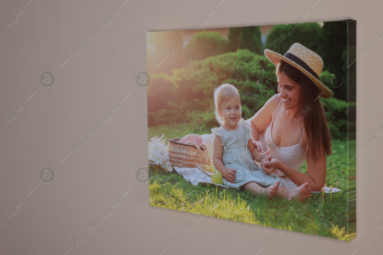 Photo of Canvas with printed photo of happy mother and her little daughter on beige wall indoors, space for text