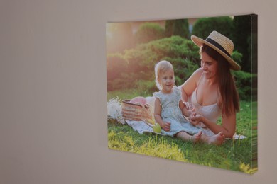 Canvas with printed photo of happy mother and her little daughter on beige wall indoors, space for text