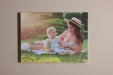 Canvas with printed photo of happy mother and her little daughter on beige wall indoors